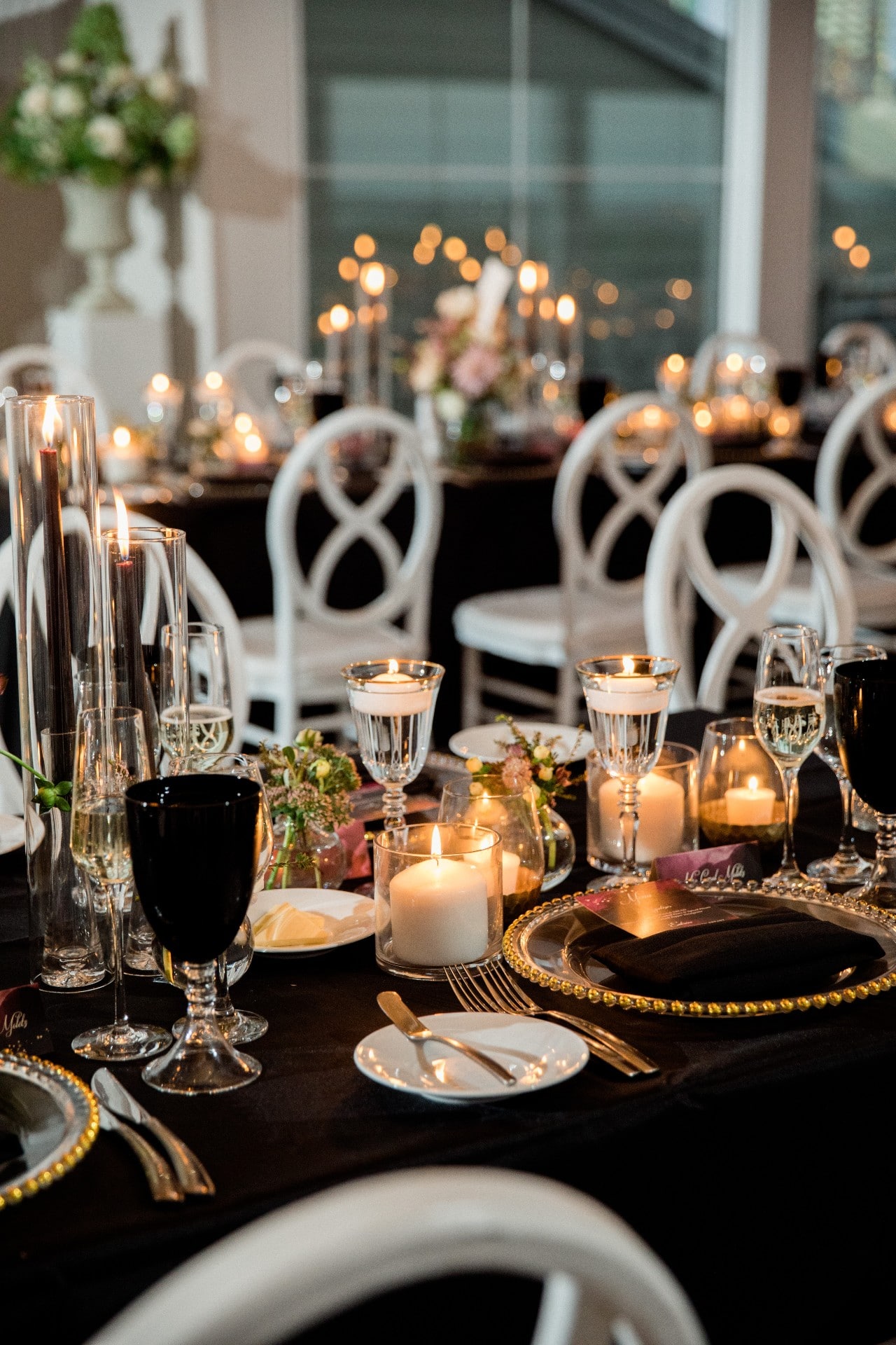black and gold tablescape floating candles white chairs