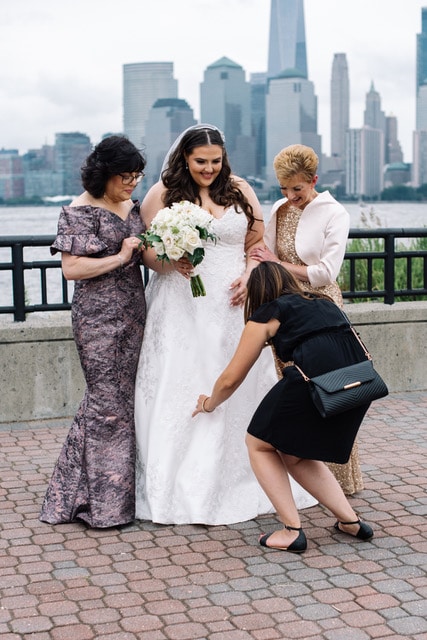 wedding planner fixing bride's dress for photos