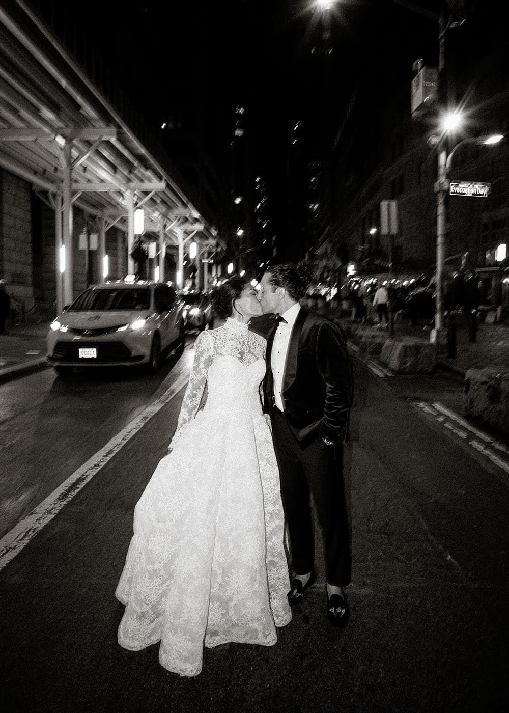 Wedding couple kissing in the street at night in NYC.